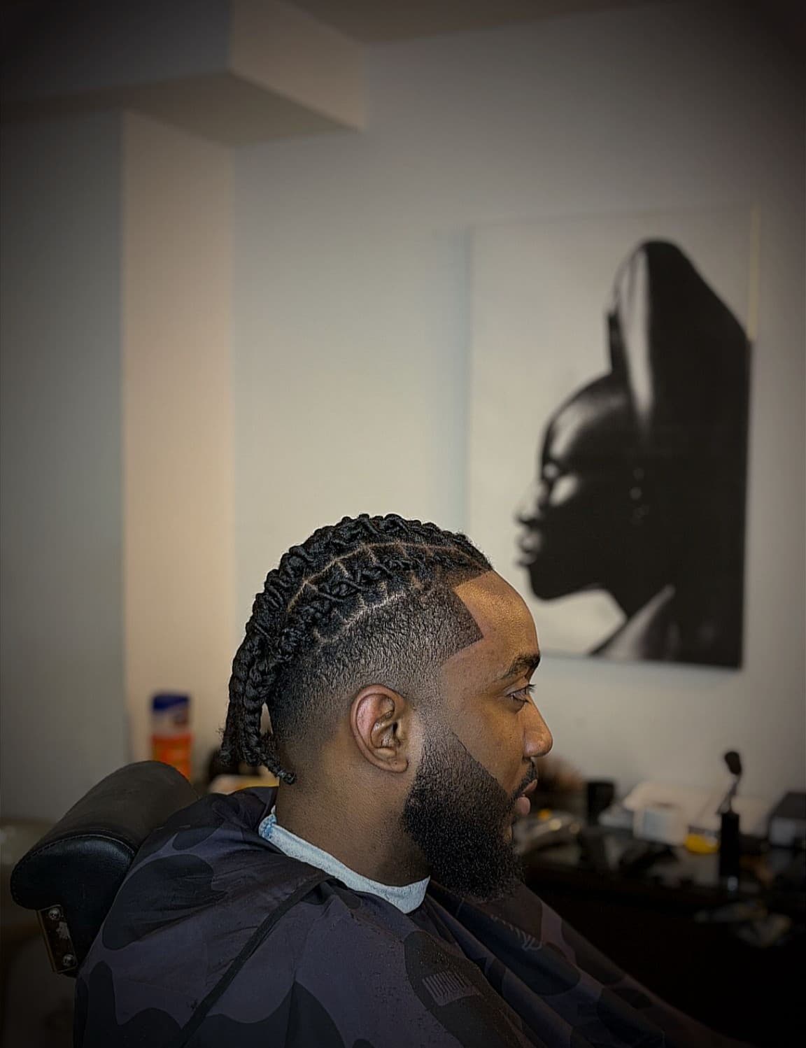 Nattes collées vers l'arrière, dégradé sur les côtés et barbe taillée, réalisé chez Christian Cutz, barbier à Préfontaine, Montréal